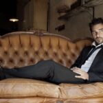 Edoardo Leo sdraiato su un sofà in giacca e cravatta