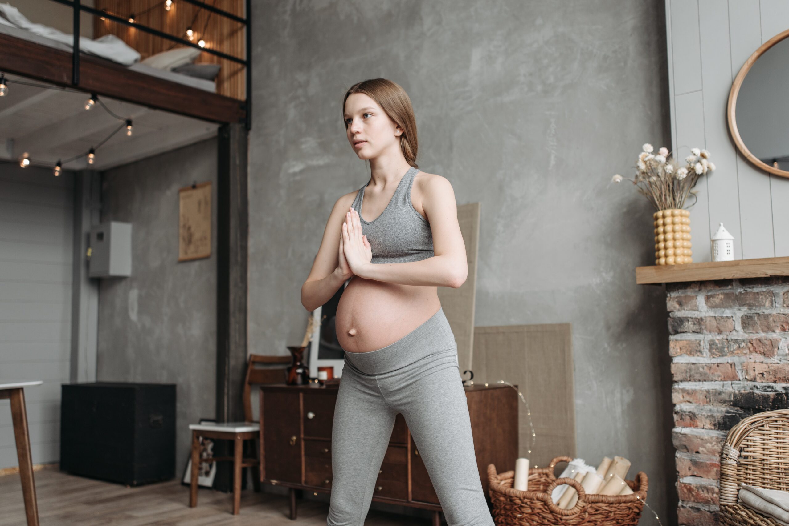 ragazza incinta fa yoga in piedi