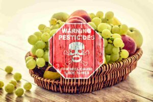 frutta nel cesto e cartello di attenzione ai pesticidi