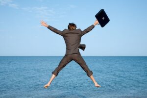 uomo che salta in mare vestito da ufficio con valigetta