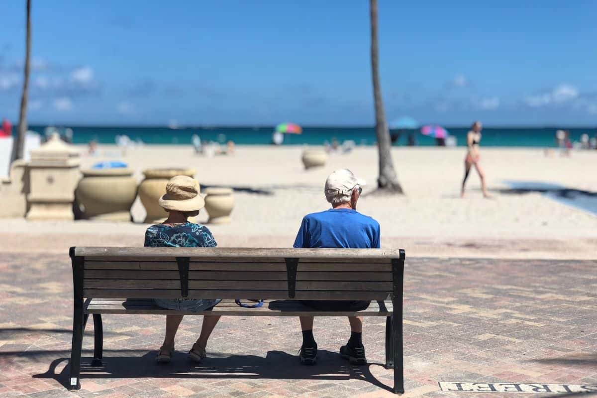 signori anziani seduti su una panchina vicino alla spiaggia e al mare
